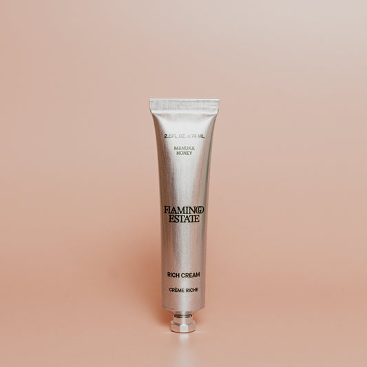 Silver tube of Flamingo Estate Rich Cream on a beige background
