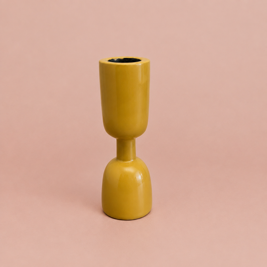 Yellow enamel taper holder on a warm blush background