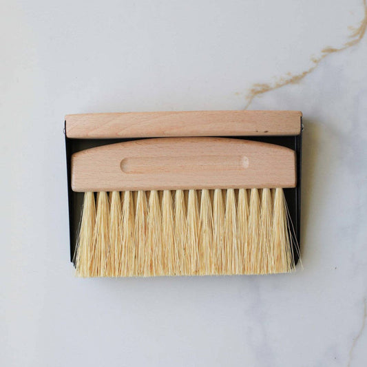 Dust brush with wooden handle and bristles in a black box on a light gray background