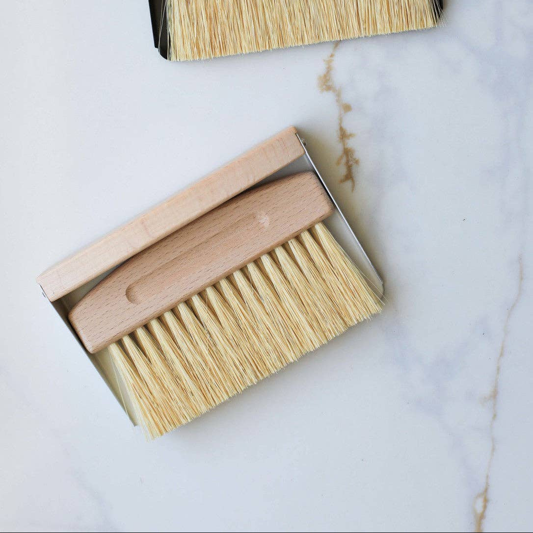 Two wooden brushes with bristle heads in black boxes on a marble surface