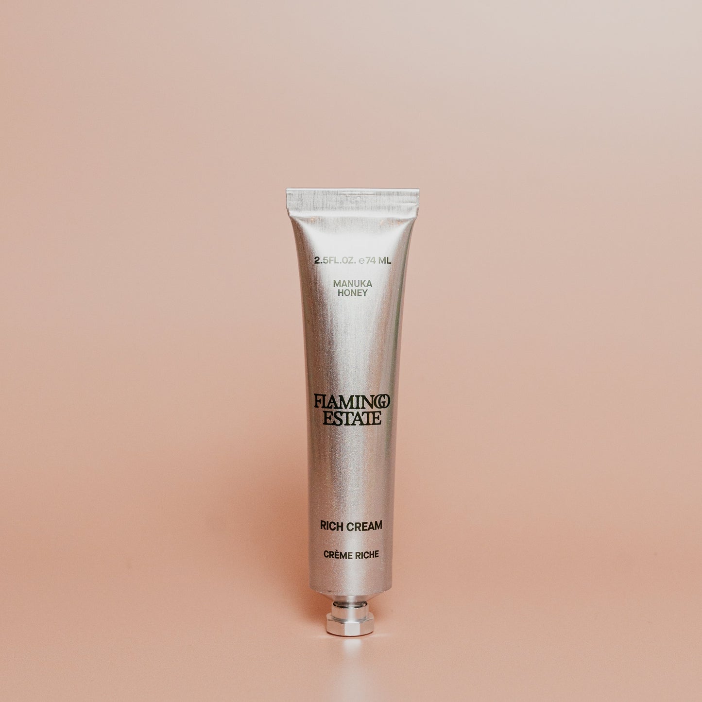 Silver tube of Flamingo Estate Rich Cream on a beige background