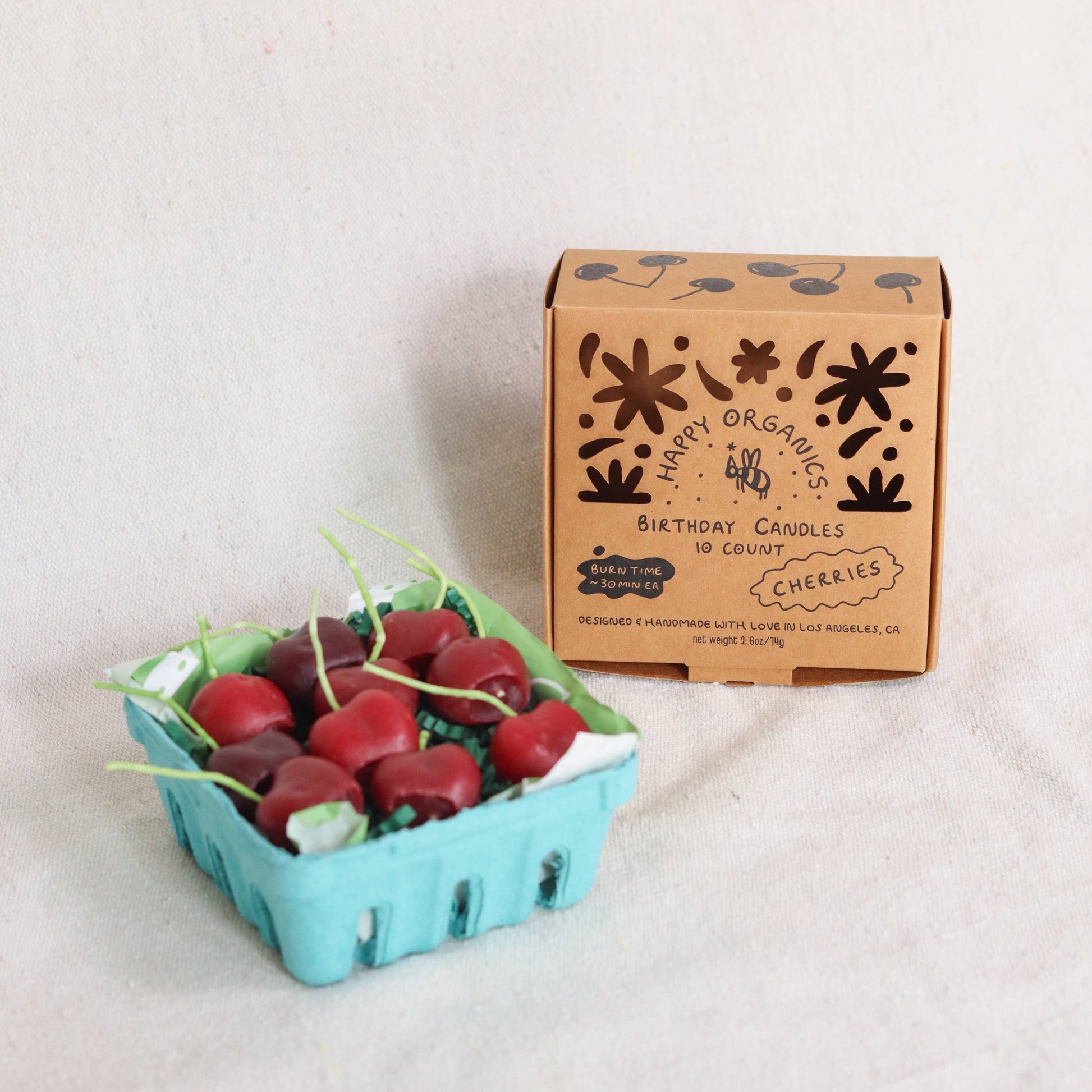 Carton of cherries birthday candles on a light background