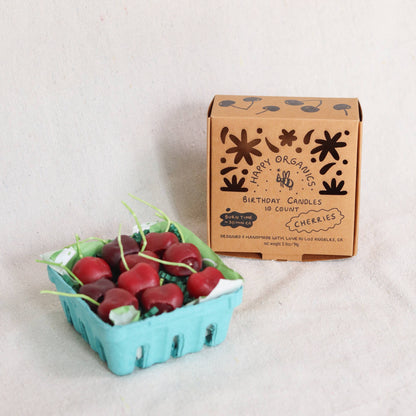 Carton of cherries birthday candles on a light background