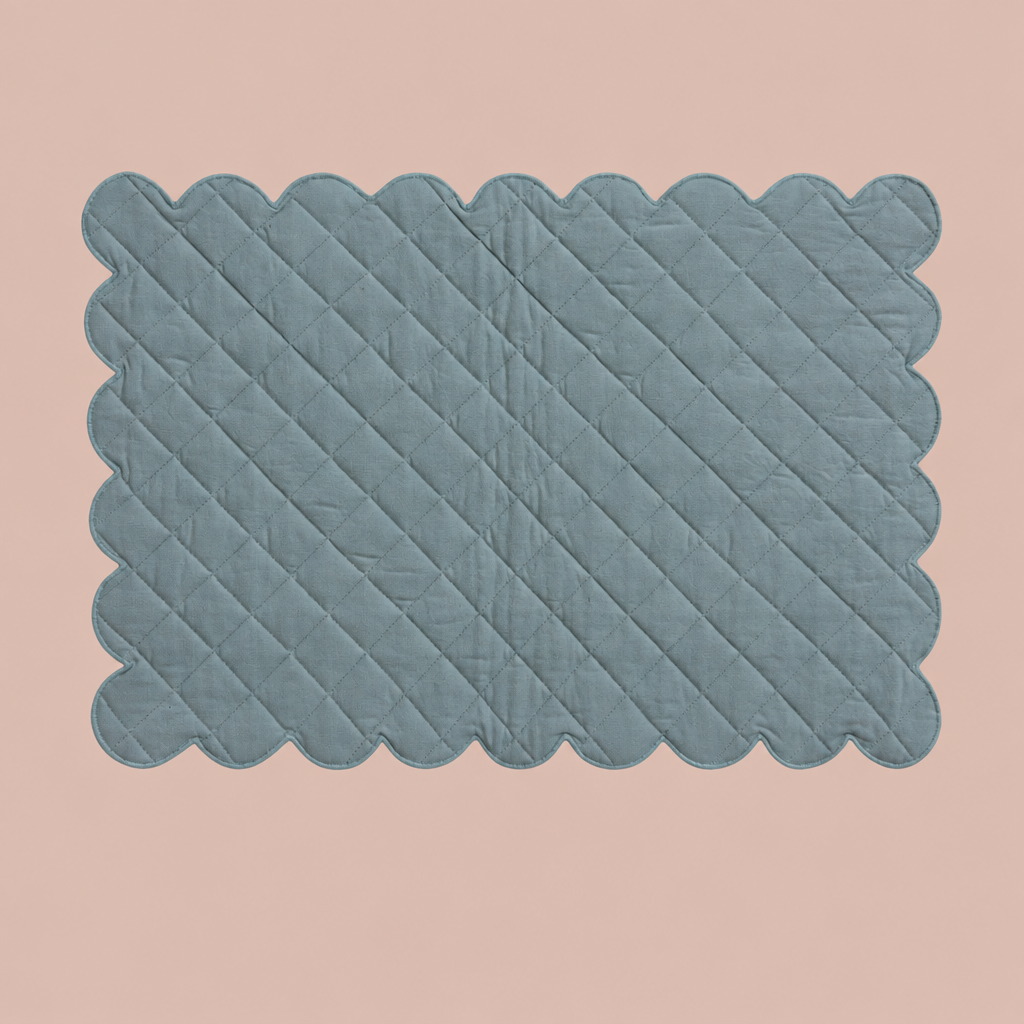 Blue quilted scalloped placemat on solid blush background