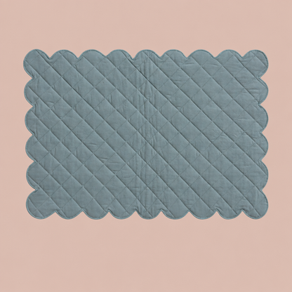 Blue quilted scalloped placemat on solid blush background