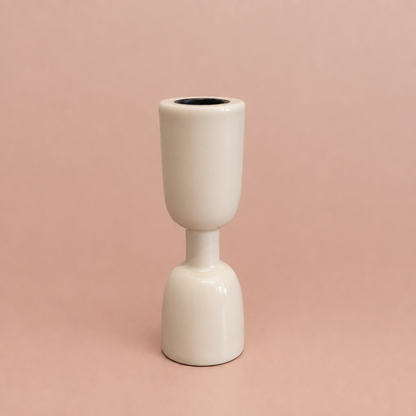 White enamel taper holder on a warm blush background
