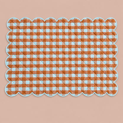 Scalloped brown and blue gingham placemat without tableware on blush background