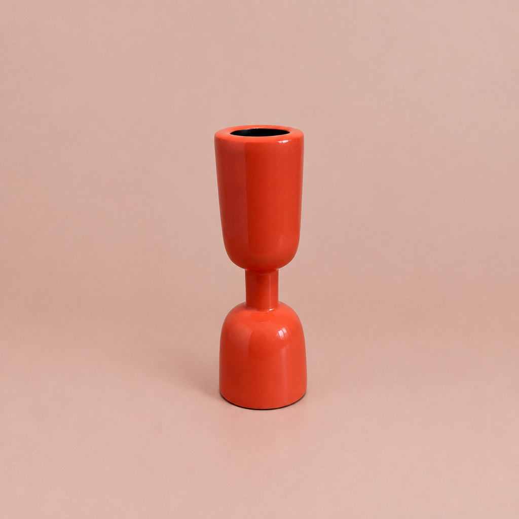 Coral enamel taper holder on a warm blush background