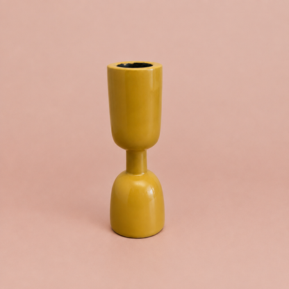 Yellow enamel taper holder on a warm blush background