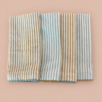Four striped cotton napkins on a blush background