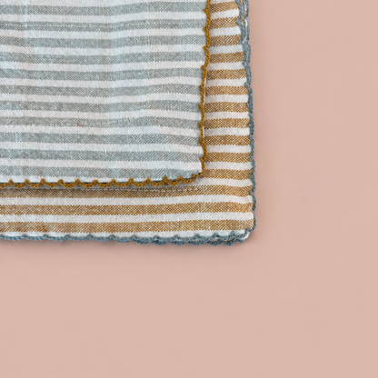 Close-up of two striped scalloped cotton napkins on blush background