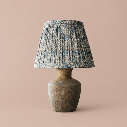 D’Oise table lamp with botanical patterned pleated shade and rustic textured base on a neutral background
